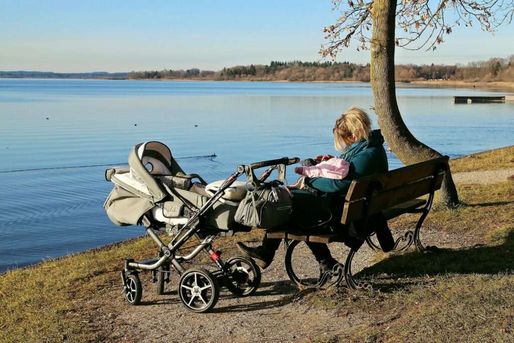 mama z dzieckiem nad jeziorem z zamontowaną do wózka torbą