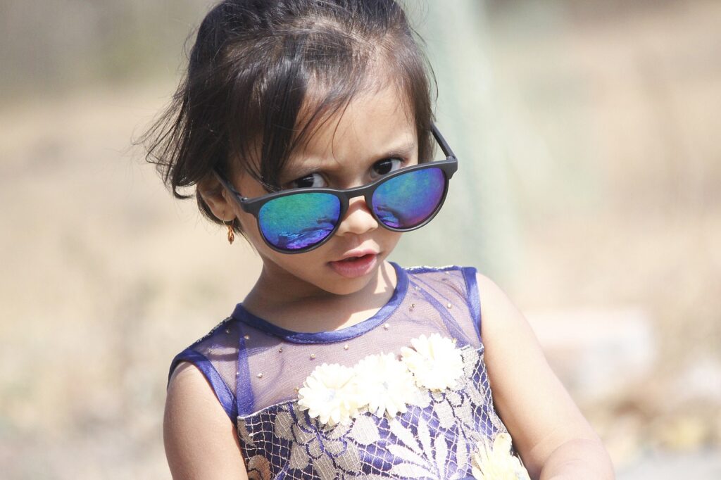 dziewczynka w ciemnych włosach z założonymi okularami przeciwsłonecznymi